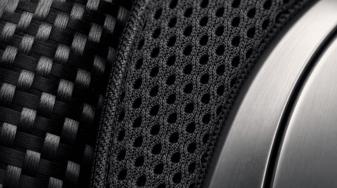 Extreme close-up macro of layered athletic materials side by side: carbon-fiber weave on the left, perforated performanc