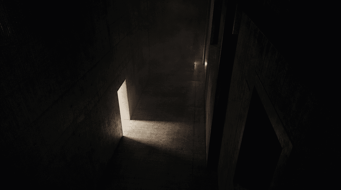 An empty concrete corridor seen from a high fixed angle, one doorway spilling a sharp rectangle of off-white light acros