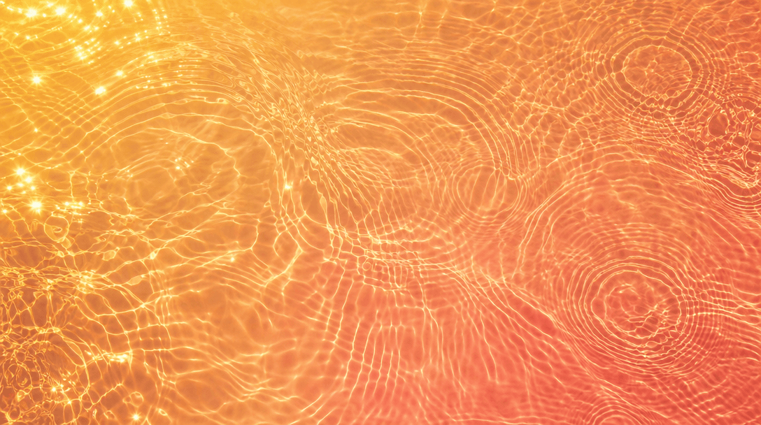 Abstract overhead view of sunlit lake water surface with warm gold reflections and gentle concentric ripples, saturated 