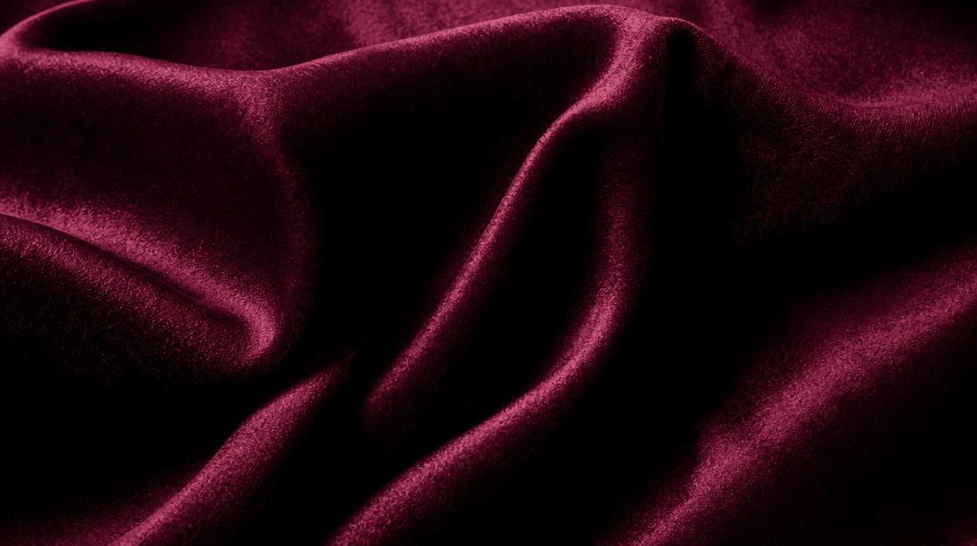 Close-up texture of luxe fabric material, rich deep colors, studio lighting highlight, fashion editorial focus