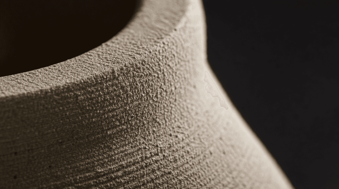 Extreme macro close-up: the unglazed surface of a raw ceramic piece — fine granular ridges and subtle pits catching raki