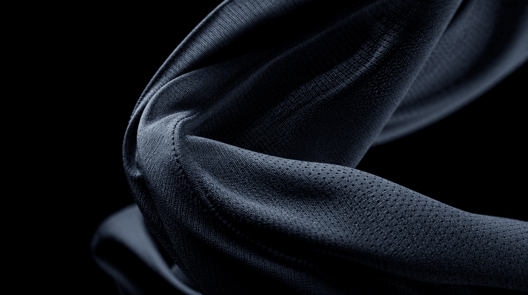 Abstract slow-motion close-up of dark athletic jersey fabric caught mid-twist — fibers, weave texture, and surface detai