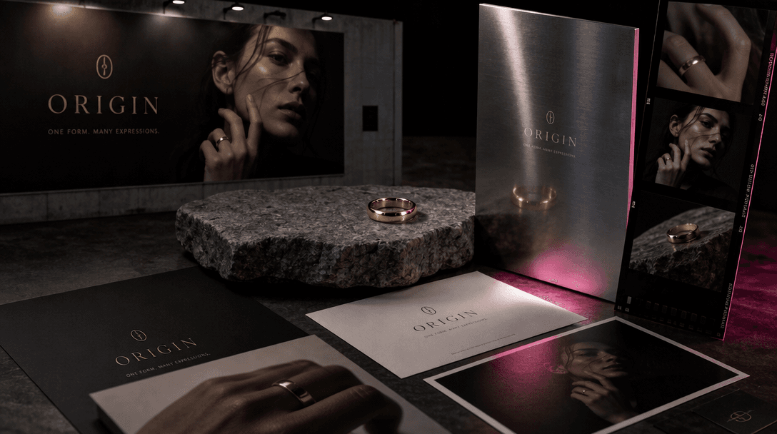 A coordinated campaign still life with one gold ring reflected across billboard paper, polished steel, stone, and photog