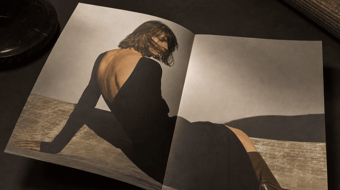 Premium matte-finish printed campaign sheet lying open on a dark editorial surface, luxury brand aesthetic implied by pr