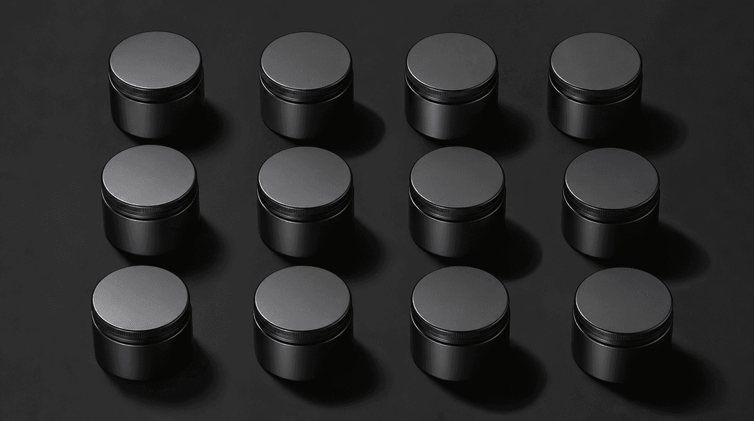 Twelve identical small supplement containers arranged in a precise 4×3 grid on matte black surface, each lit from a slig