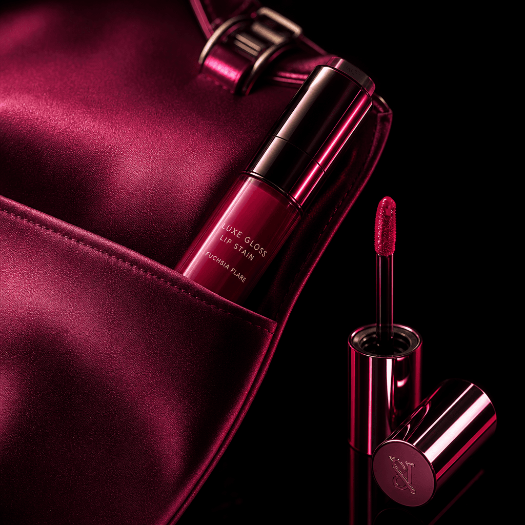 A glossy lip stain nested in the pocket of a satin evening bag, applicator and reflective cap arranged beside it as a re