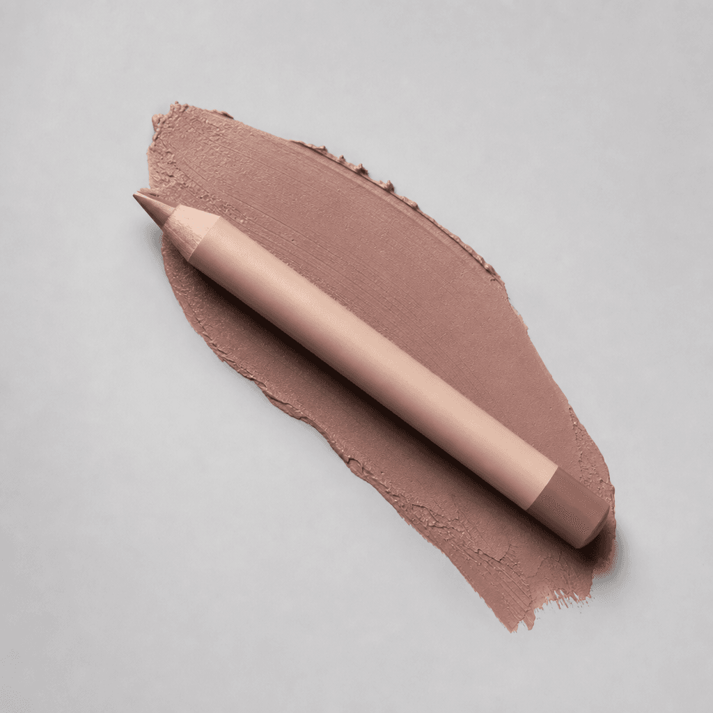 Nude beige lip liner pencil placed at a precise angle over a warm taupe smear on a light grey studio backdrop, diffused 