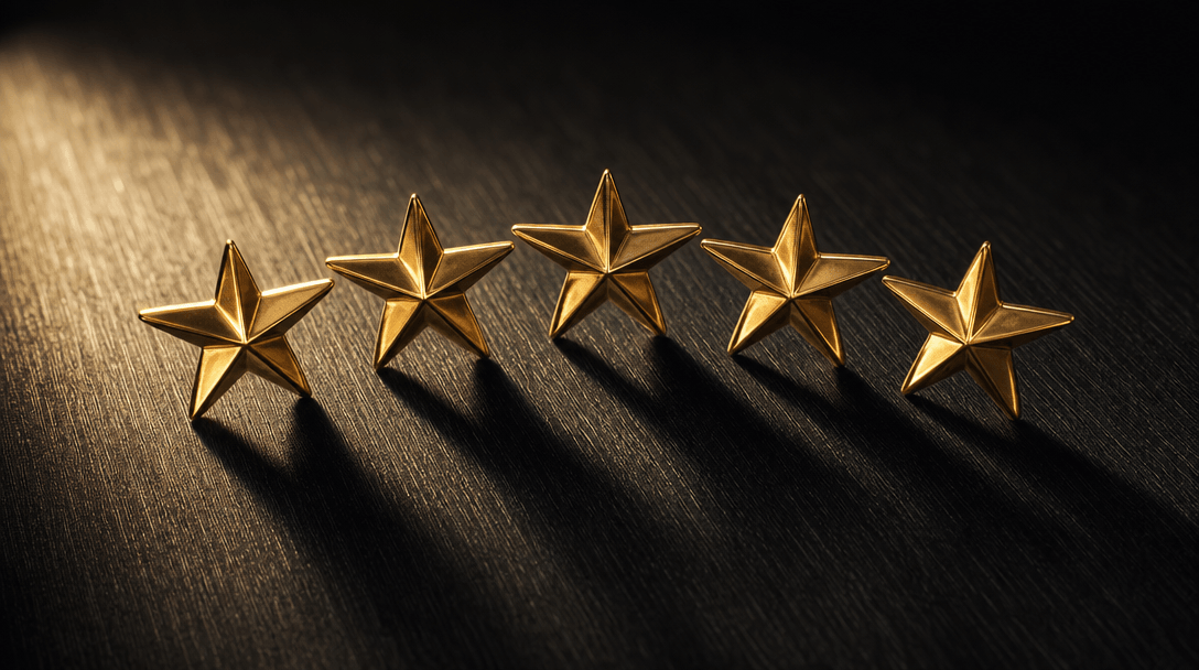 Abstract macro photograph: five polished solid gold stars arranged in a gentle horizontal arc, resting on a brushed obsi