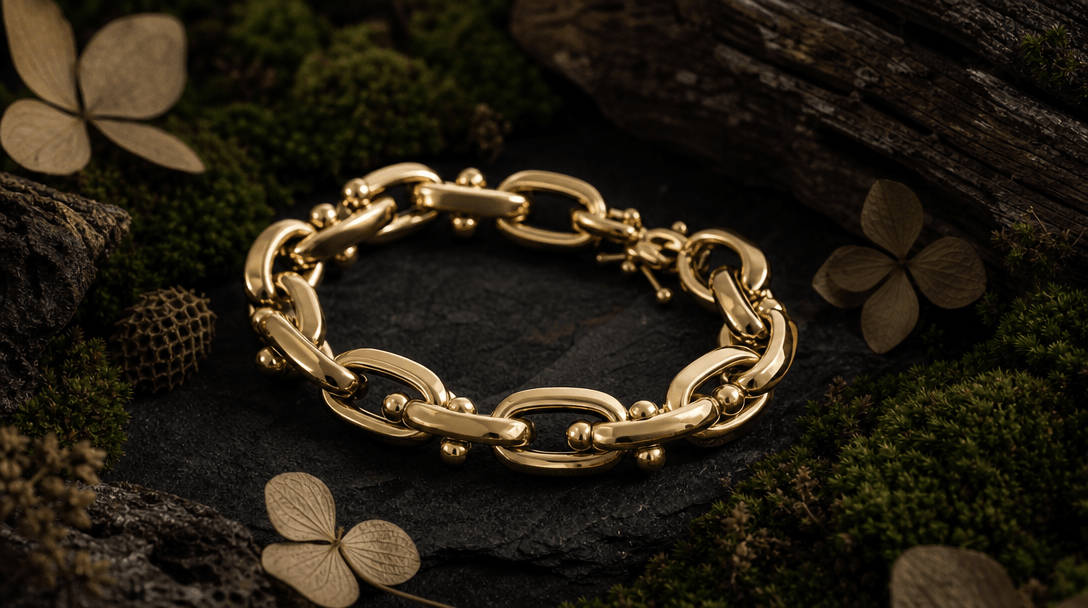 Close-up product shot of a polished gold bracelet on a deep editorial dark surface, illuminated by a single soft side-li