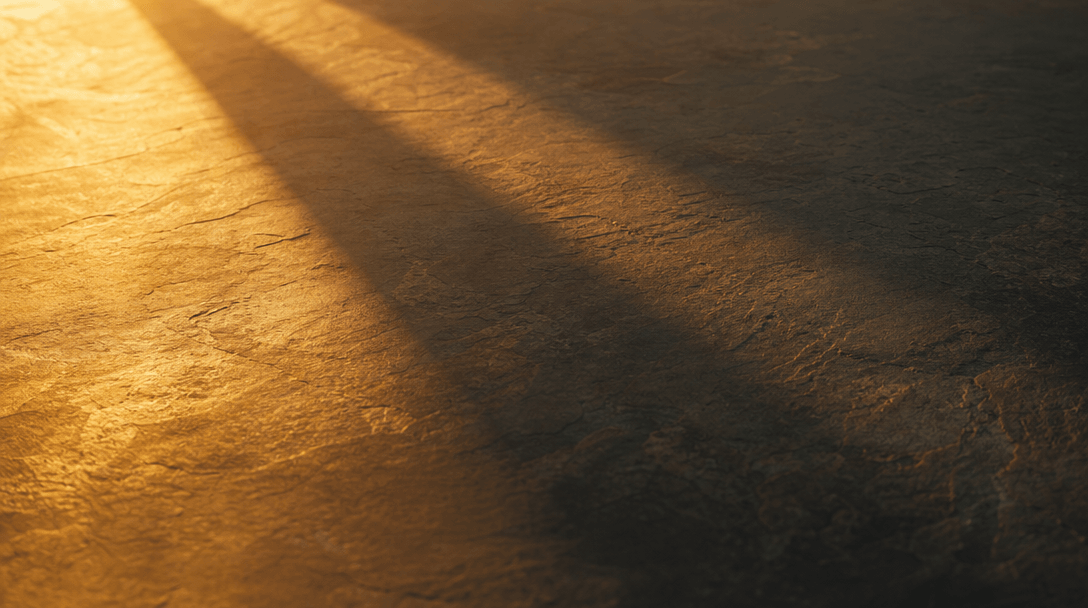 Warm natural sunlight ray raking at a low angle across a smooth stone surface, casting a long soft directional shadow th