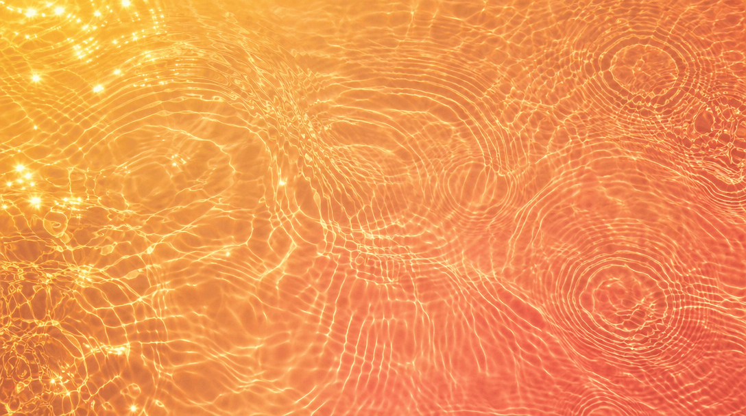 Abstract overhead view of sunlit lake water surface with warm gold reflections and gentle concentric ripples, saturated 