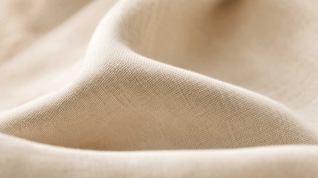 Softly lit luxury fabric texture—silk, cotton, or wool weave—with subtle motion blur. Warm studio lighting, minimalist s