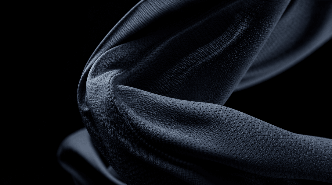 Abstract slow-motion close-up of dark athletic jersey fabric caught mid-twist — fibers, weave texture, and surface detai