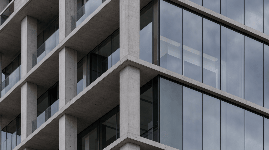 Close-up detail of a concrete and glass building facade showing precise floor slab edges, column rhythm, and reflective 