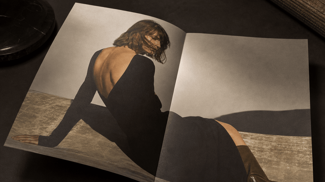 Premium matte-finish printed campaign sheet lying open on a dark editorial surface, luxury brand aesthetic implied by pr