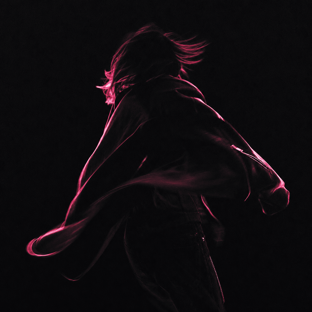 Fashion editorial still: silhouetted figure caught mid-motion against a deep black background, soft neon pink rim light