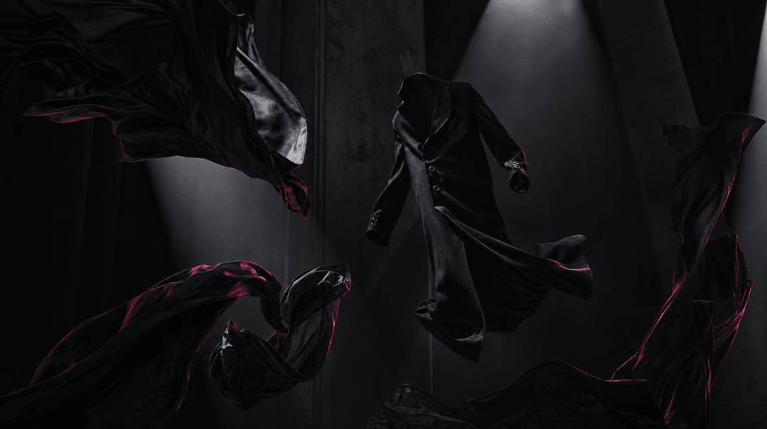 A black tailored coat and sheets of dark fabric floating weightlessly inside a tall shadowed studio, materials twisting 