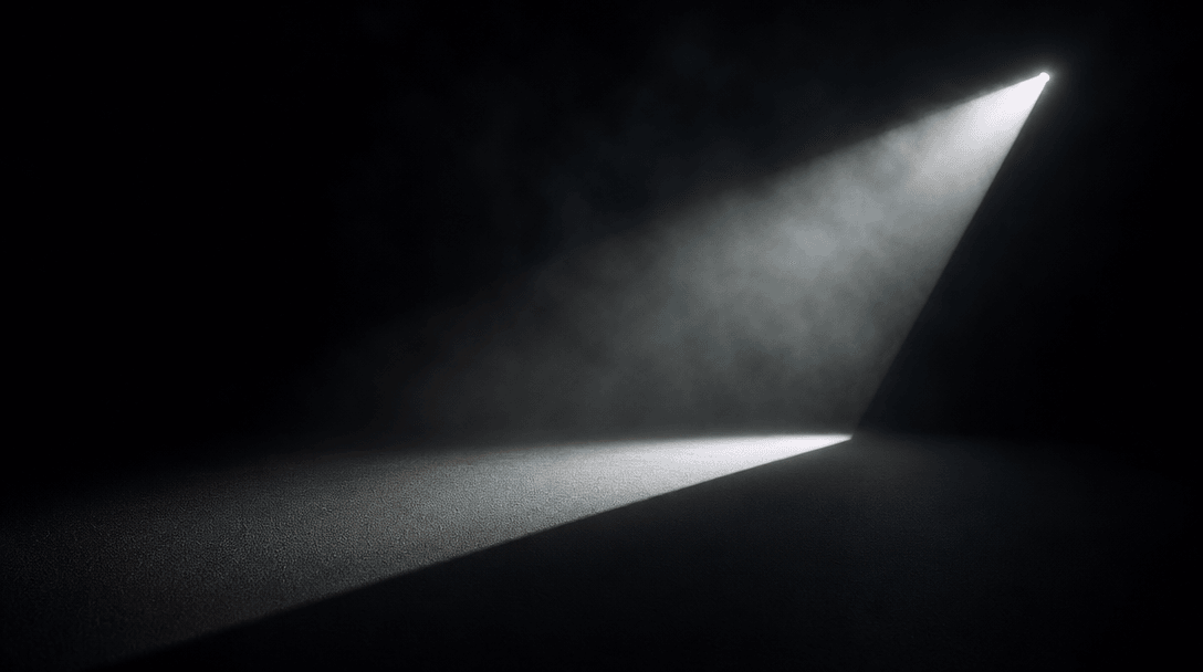 Abstract studio lighting composition: a single hard light source on a seamless dark surface near #0A0A0F casting a sharp