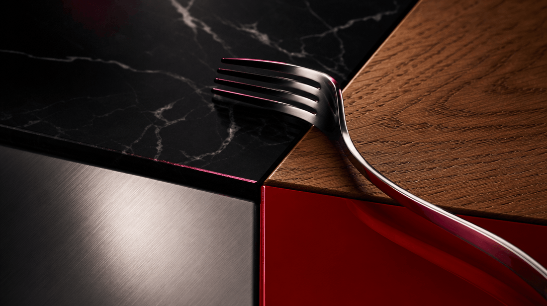Four distinct dining materials meeting in one refined composition: black marble, warm oak, brushed steel, and vivid red 
