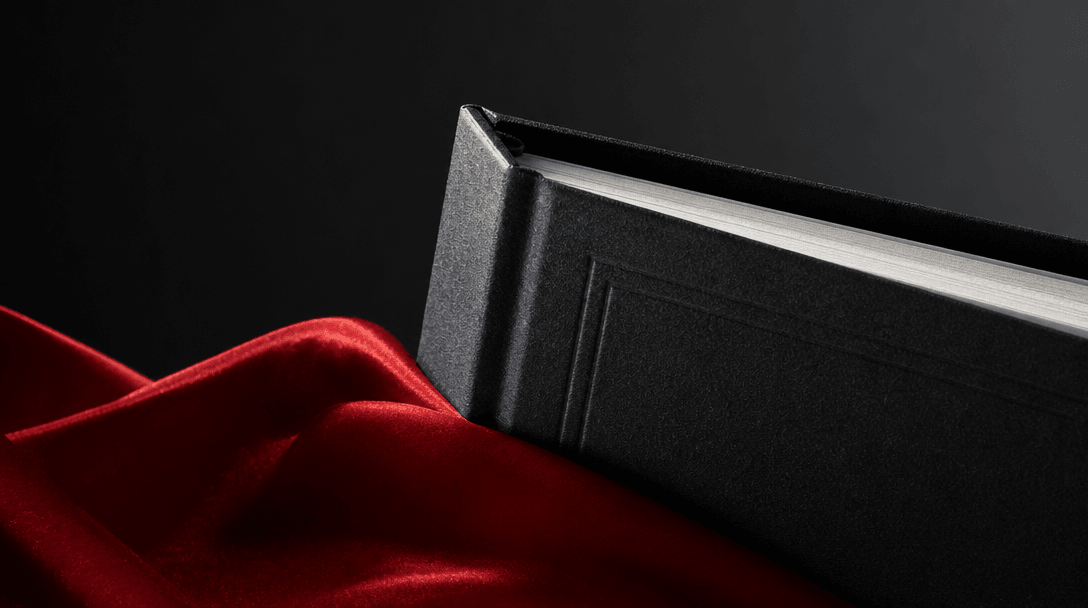 Macro editorial study of a hardcover book corner emerging from red satin, crisp paper layers, embossed material, sharp e