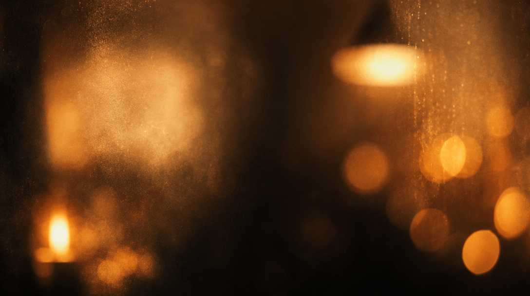 Abstract cinematic texture study of warm interior light, deep amber bokeh blooming from a candle and pendant lamp source