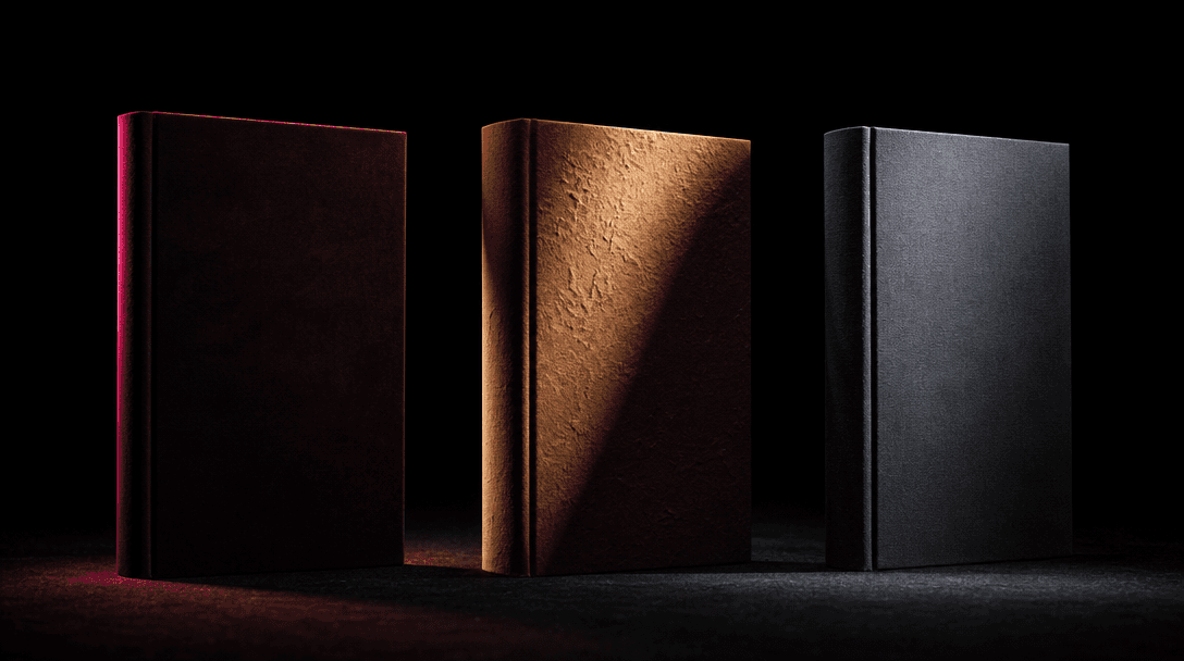 Three upright blank book jackets arranged as a deliberate triptych on a matte black studio floor, each illuminated by a