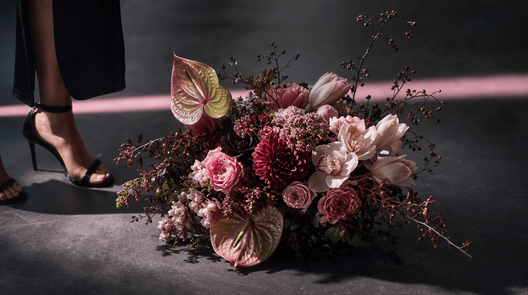 A finished floral marketing scene prepared like a premium campaign still: sculptural bouquet centered on charcoal paveme