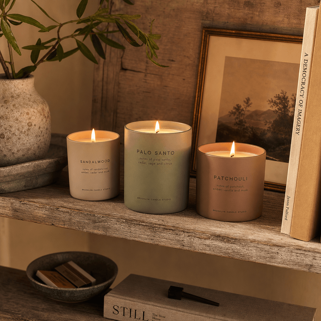 Lit candles on weathered wooden shelf, warm ambient lighting casting natural shadows, cozy product styling, professional