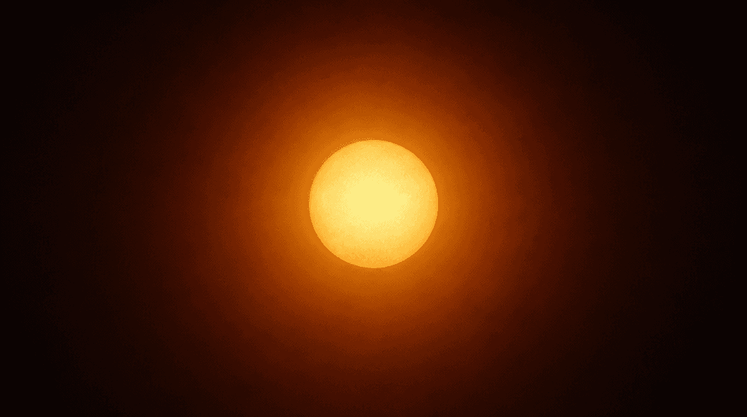 Abstract editorial photograph of a warm luminous sphere of golden-amber light against a deep dark gradient background, s