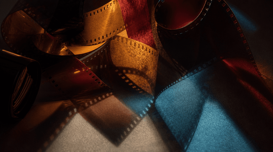 Abstract cinematic still life representing analog color direction: overlapping translucent film strips, burgundy, amber,