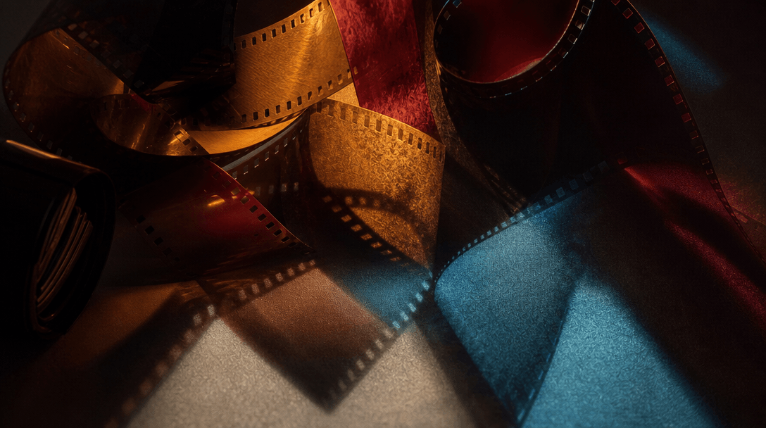 Abstract cinematic still life representing analog color direction: overlapping translucent film strips, burgundy, amber,