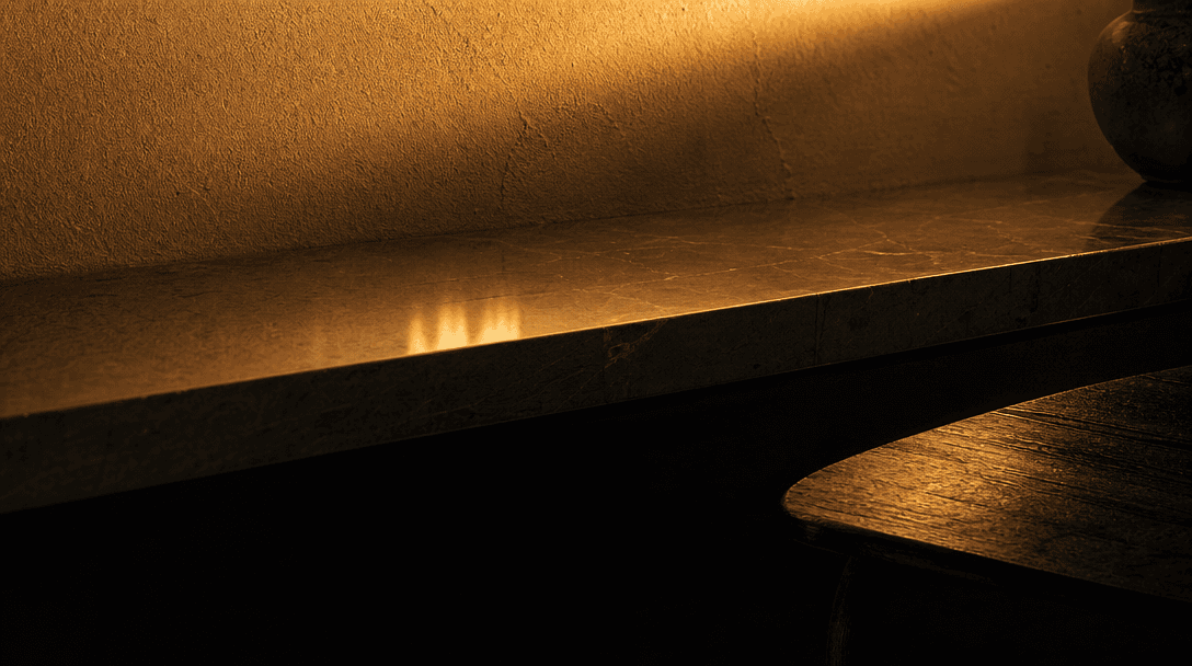 Abstract macro close-up of light falling across layered interior surfaces at dusk. Warm amber gradient washing over text