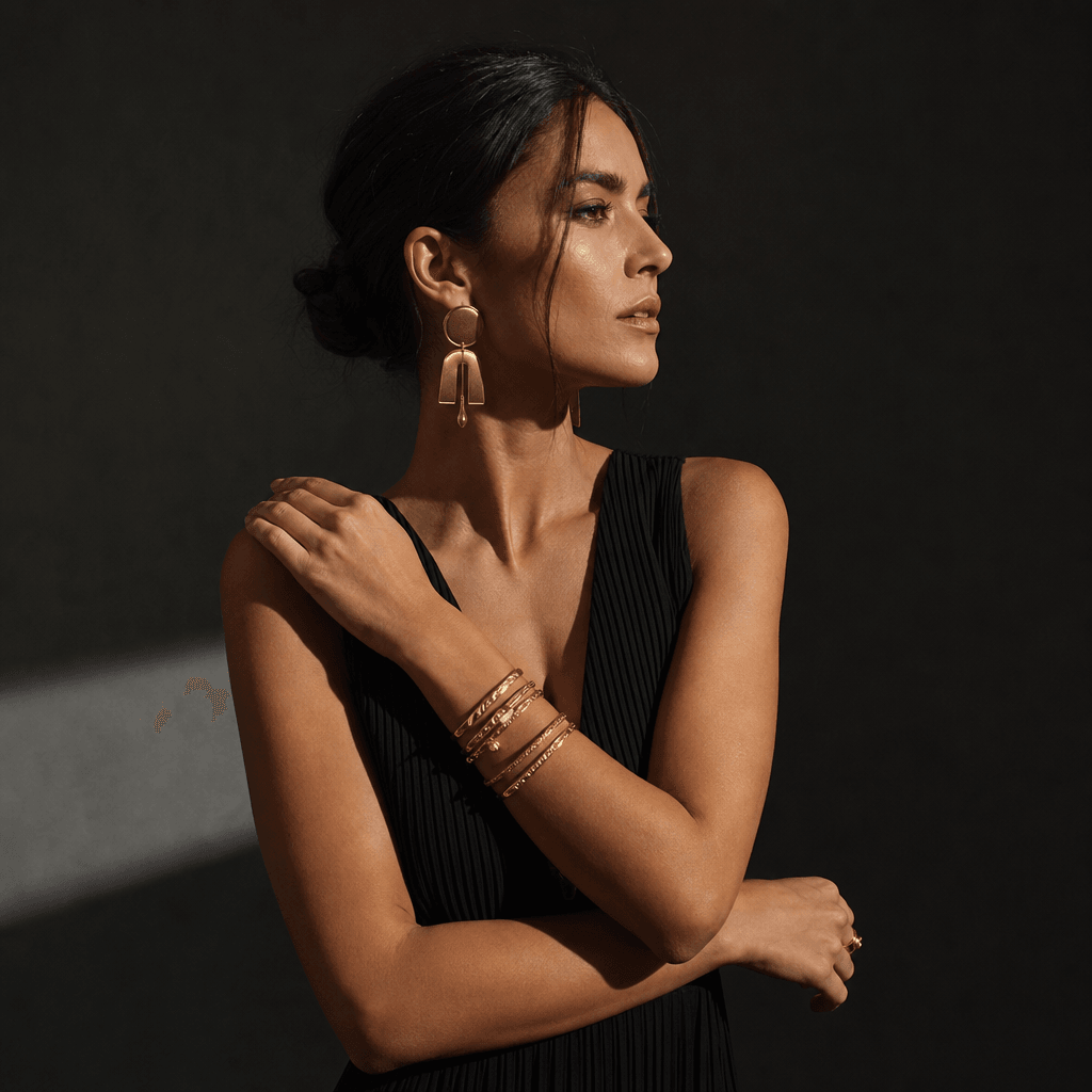 Statement jewelry styling: sleek black minimalist dress with prominent gold earrings and layered bracelet jewelry, confi