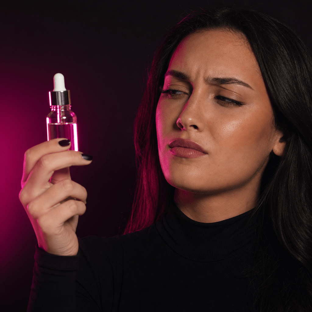 An anonymous beauty creator holding a premium serum bottle with a skeptical yet composed reaction, dark editorial studio