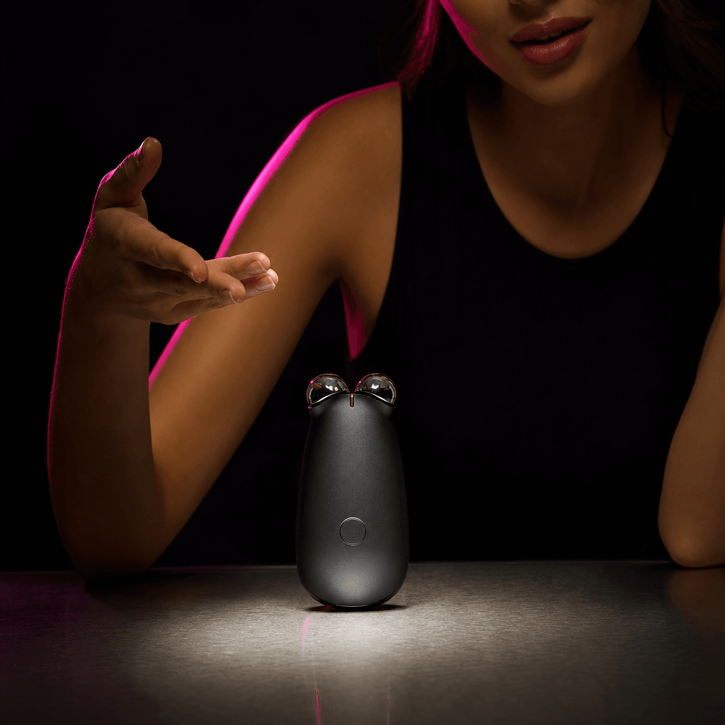 A compact electronic beauty device centered on a brushed metal table, an anonymous creator gesturing confidently beside
