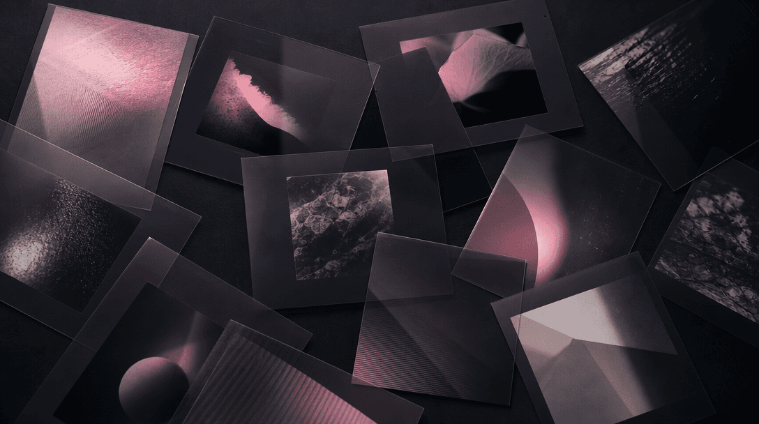 Abstract overhead flat-lay: multiple overlapping translucent dark film frames or matte cards arranged on a deep charcoal