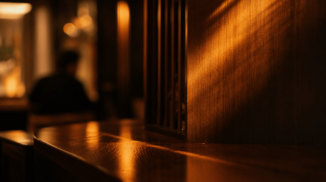 Abstract close-up of warm amber light rays falling across dark polished wood surfaces in a restaurant interior, soft dep