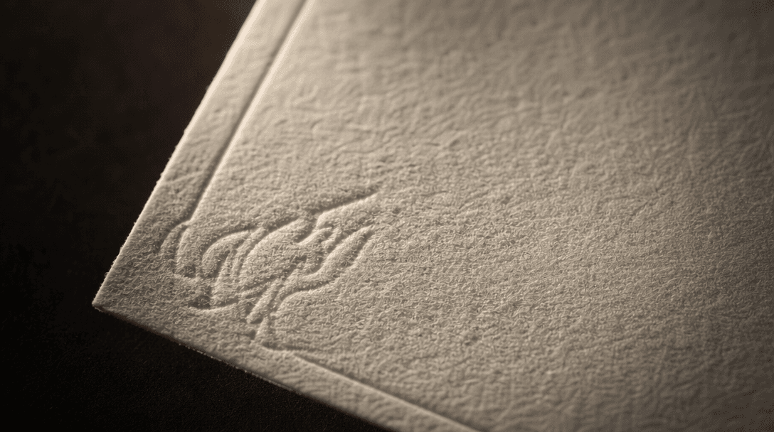 Extreme macro texture study of premium cream cotton paper with a subtly embossed press pattern, raking warm directional